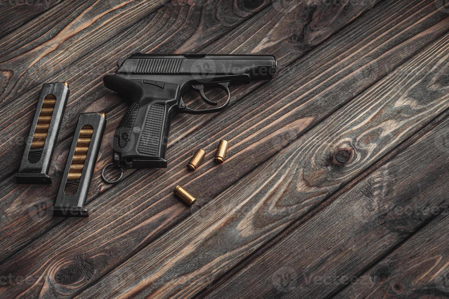 A modern black pistol and ammunition on dark wooden background. Weapons for police, army, special forces. photo