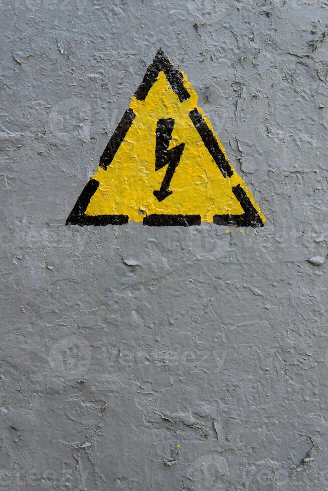 The sign of electrical hazard on a gray coarse metaic painted surface photo