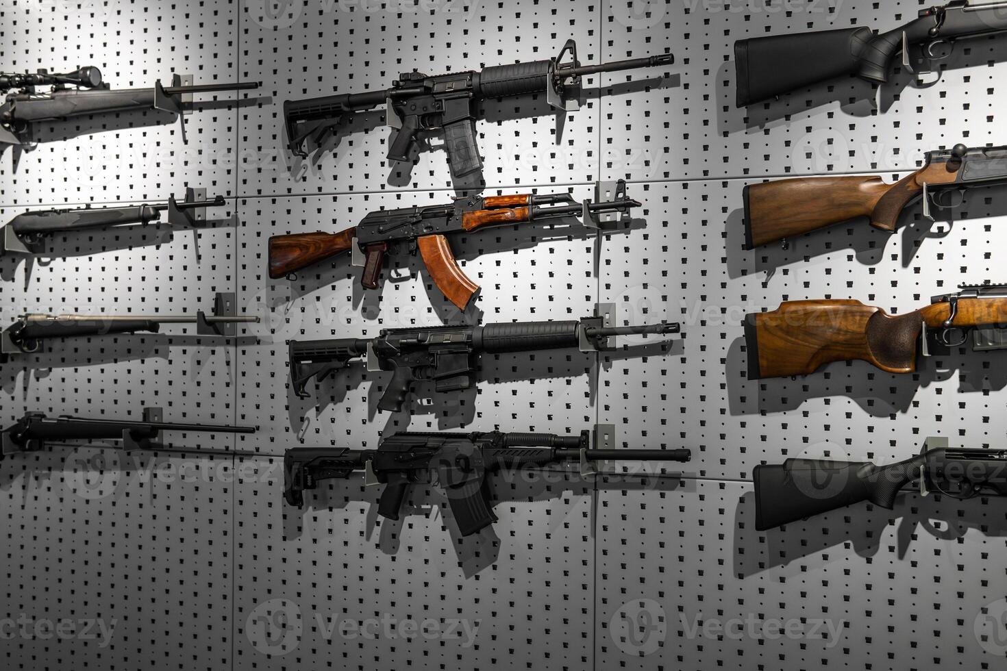 Collection of rifles and carbines. Various firearms hang on special mounts on the wall. Weapon back photo