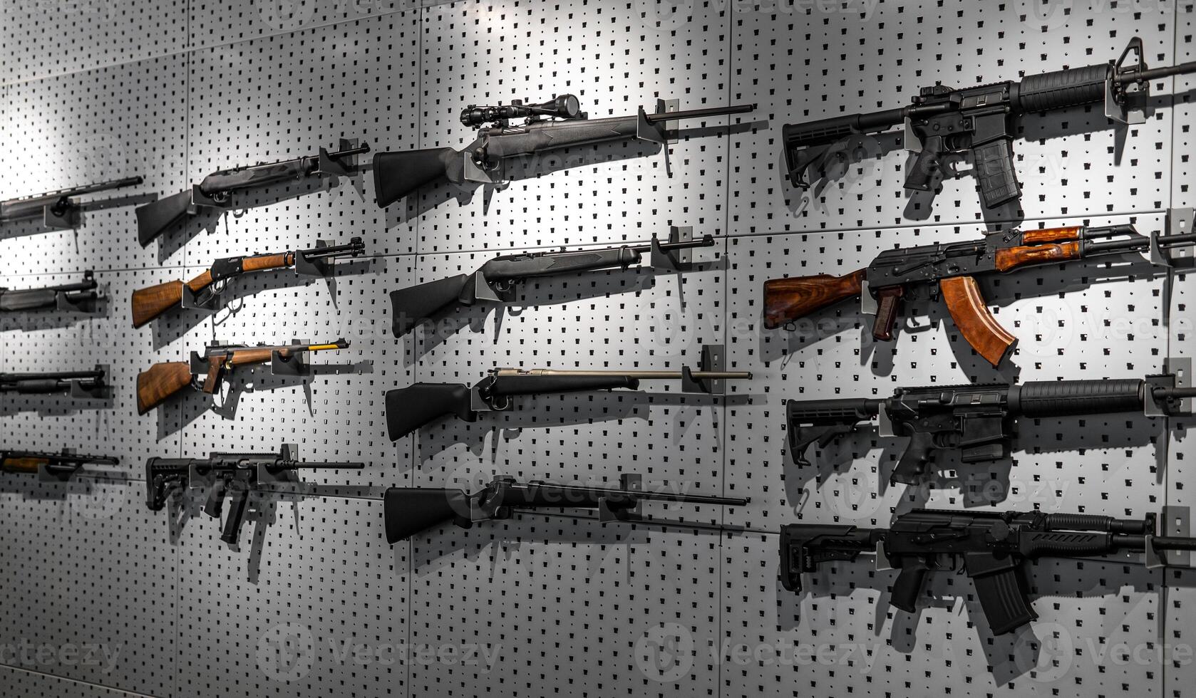 Collection of rifles and carbines. Various firearms hang on special mounts on the wall. Weapon back photo