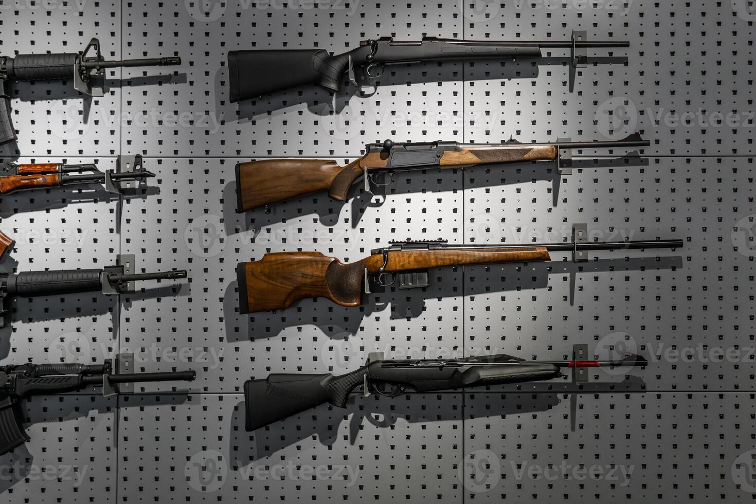 Collection of rifles and carbines. Various firearms hang on special mounts on the wall. Weapon back photo