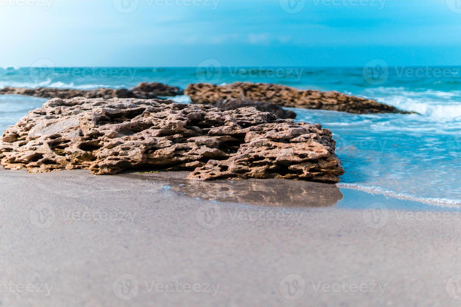 Soft wave crashing stone at bay. Stones by the sea. Sea wave breaks on beach rocks landscape. Sea waves crash and splash on rocks. Beach rock sea wave breaking. photo