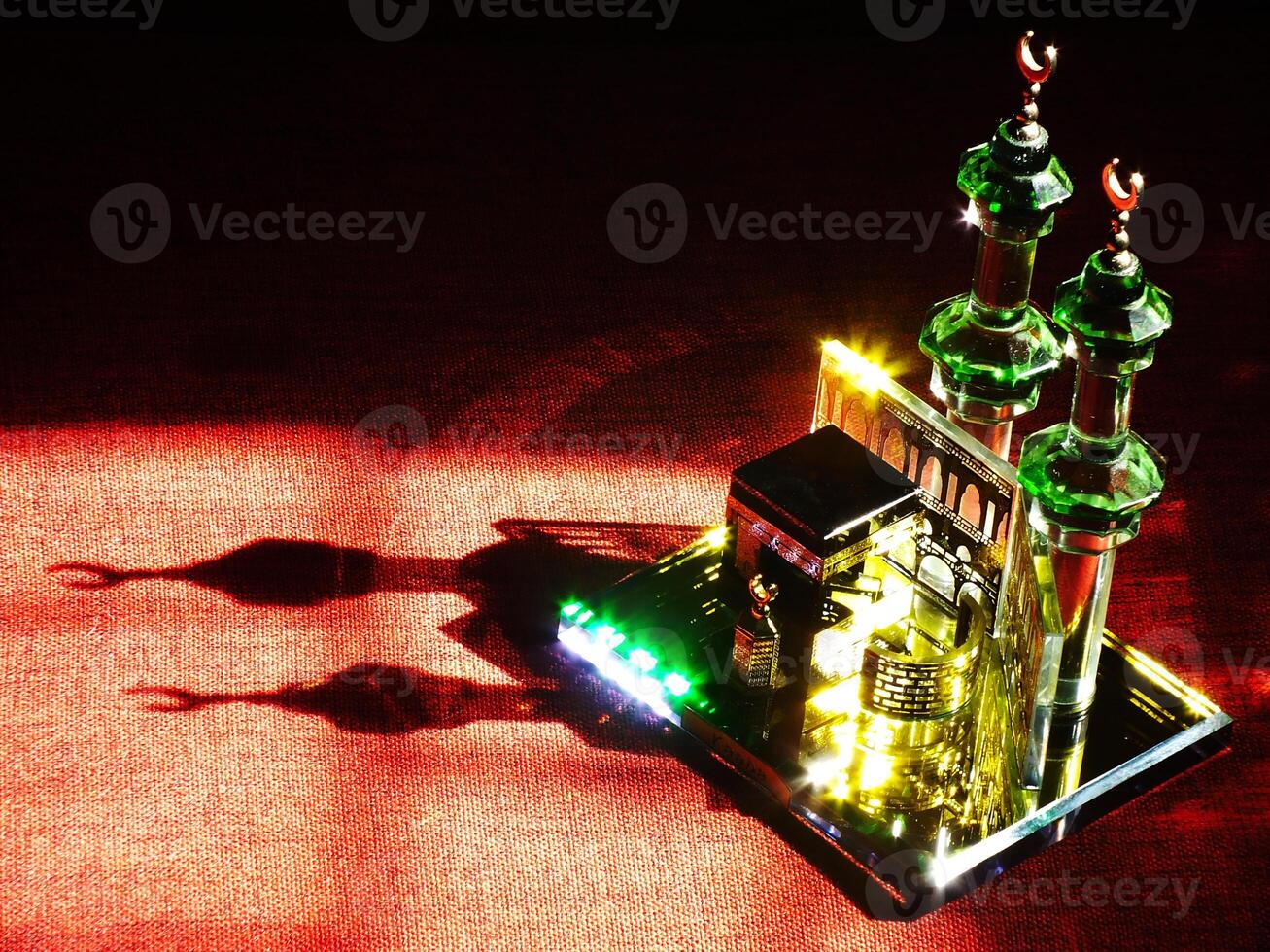 Small model of the Kaaba, the holy mosque of the Grand Mosque, Mecca, isolated on a dark background. There is sunlight coming performing an amazing shadow and shining reflection photo