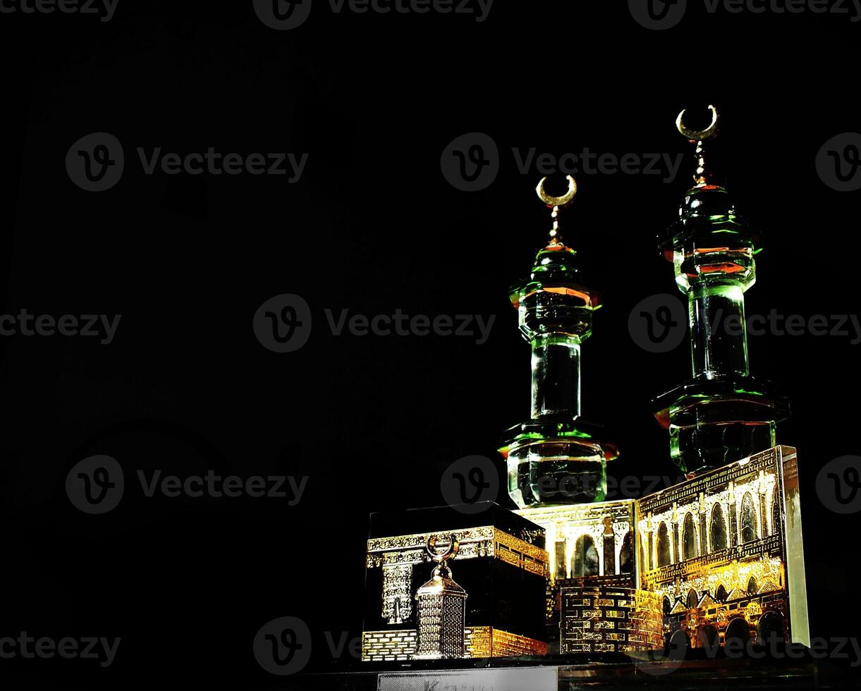 Small model of the Kaaba, the holy mosque of the Grand Mosque, Mecca, isolated on a dark background. There is sunlight coming performing an amazing shadow and shining reflection photo