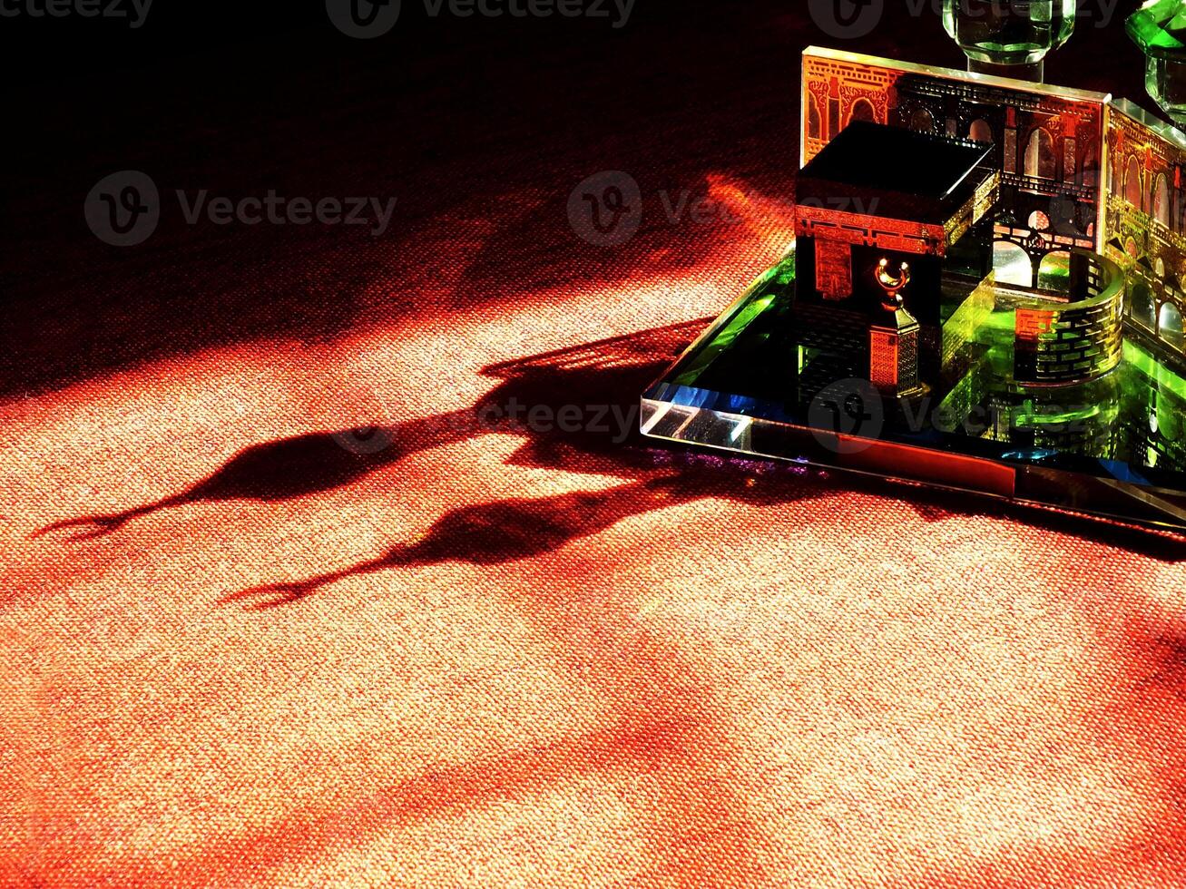 Small model of the Kaaba, the holy mosque of the Grand Mosque, Mecca, isolated on a dark background. There is sunlight coming performing an amazing shadow and shining reflection photo