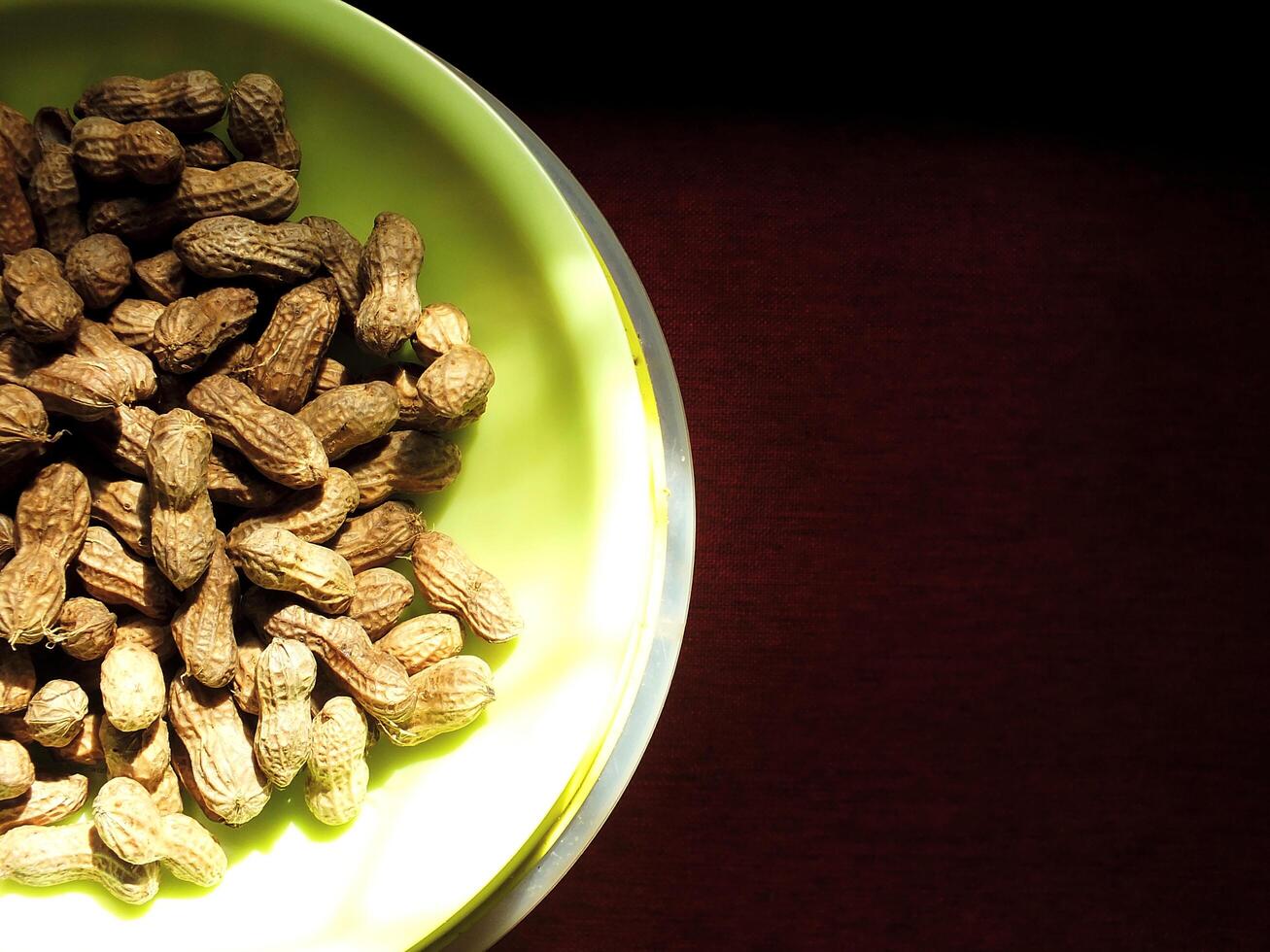 a pile of fresh peanuts on green tray with dark background. Natural light from window. Rural ambience of morning sunlight photo
