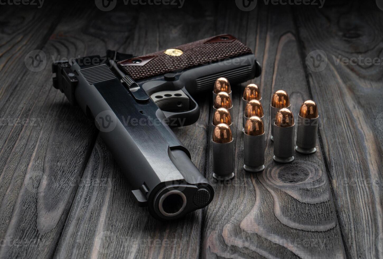 Pistol and cartridges for it on a wooden backg. A short-barreled weapon for self-defense. photo