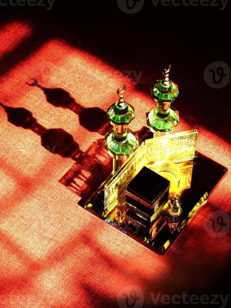 Small model of the Kaaba, the holy mosque of the Grand Mosque, Mecca, isolated on a dark background. There is sunlight coming performing an amazing shadow and shining reflection photo