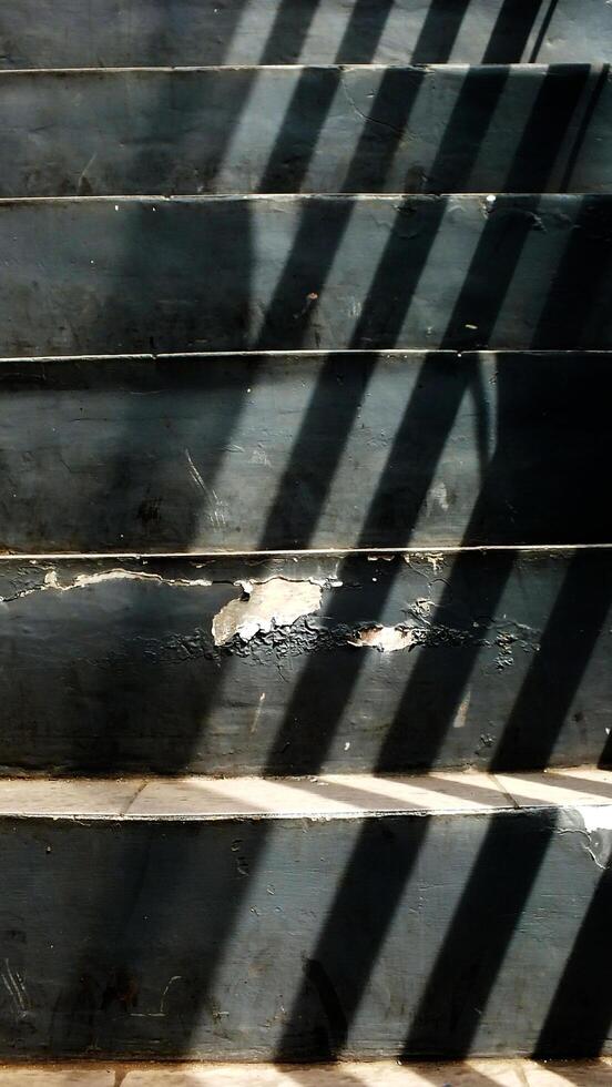 Abstract background texture of a staircase with a geometric shadow cast on it. The shadow is on the steps and the steps are grey photo