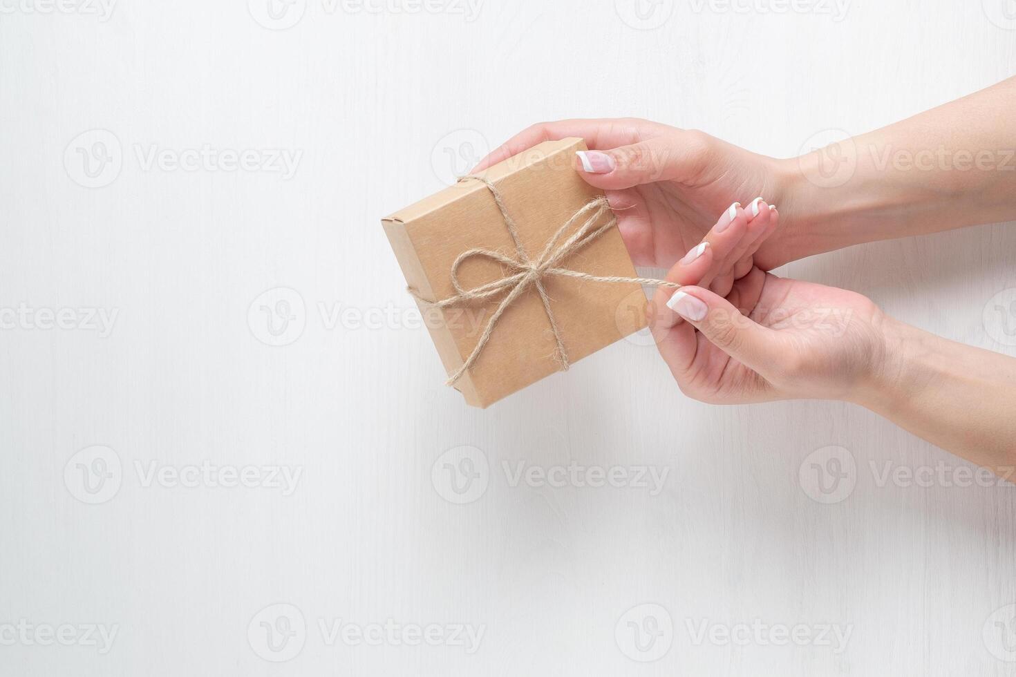hands of a young girl opening a gift box on a white background photo