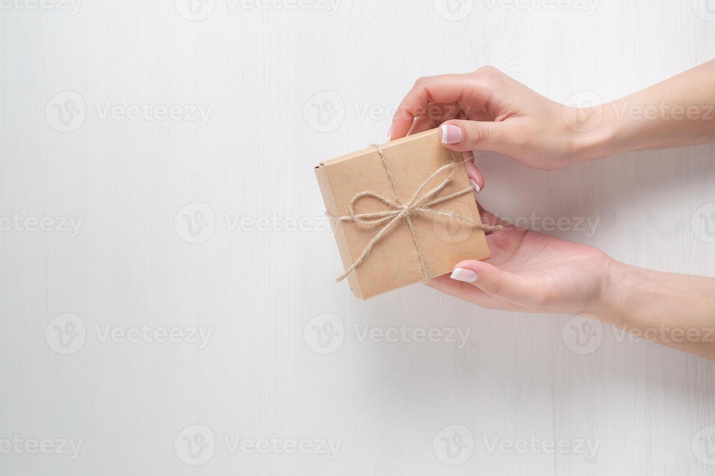 hands of a young girl opening a gift box on a white background photo