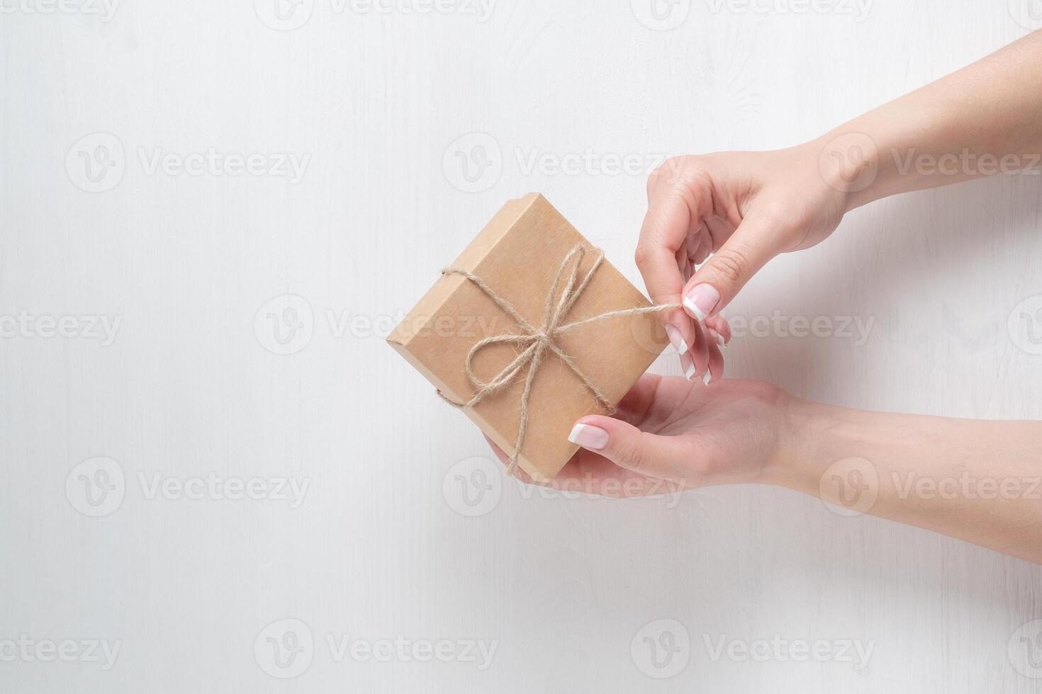 hands of a young girl opening a gift box on a white background photo