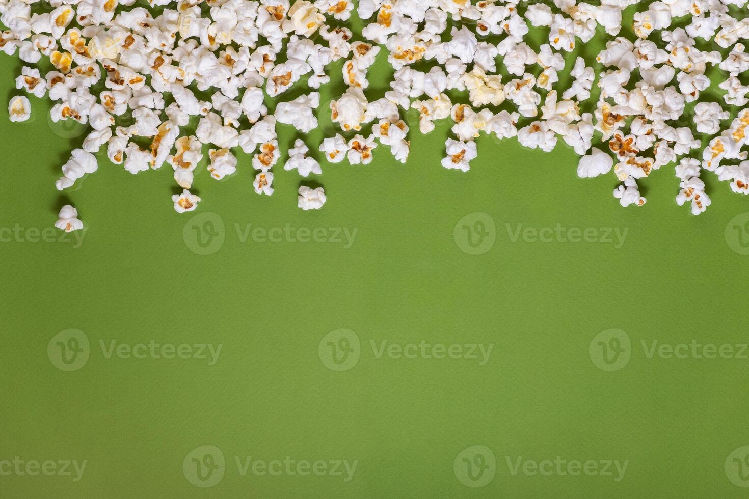 White tasty popcorn on a green background. Popcorn pattern on green background. Top view. Copyspace for your text. photo