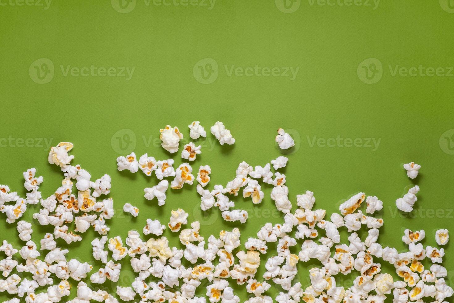 White tasty popcorn on a green background. Popcorn pattern on green background. Top view. Copyspace for your text. photo