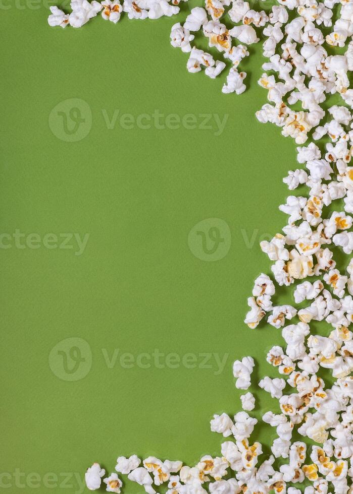 White tasty popcorn on a green background. Popcorn pattern on green background. Top view. Copyspace for your text. photo