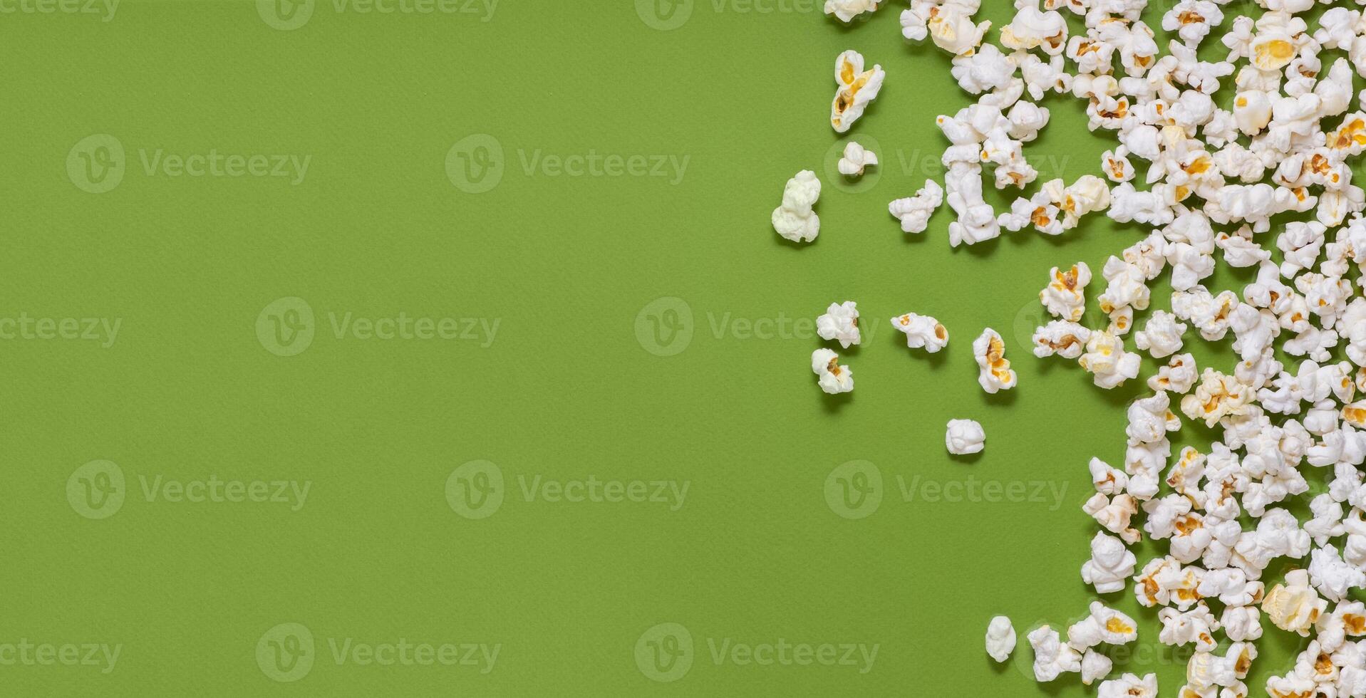 White tasty popcorn on a green background. Popcorn pattern on green background. Top view. Copyspace for your text. photo