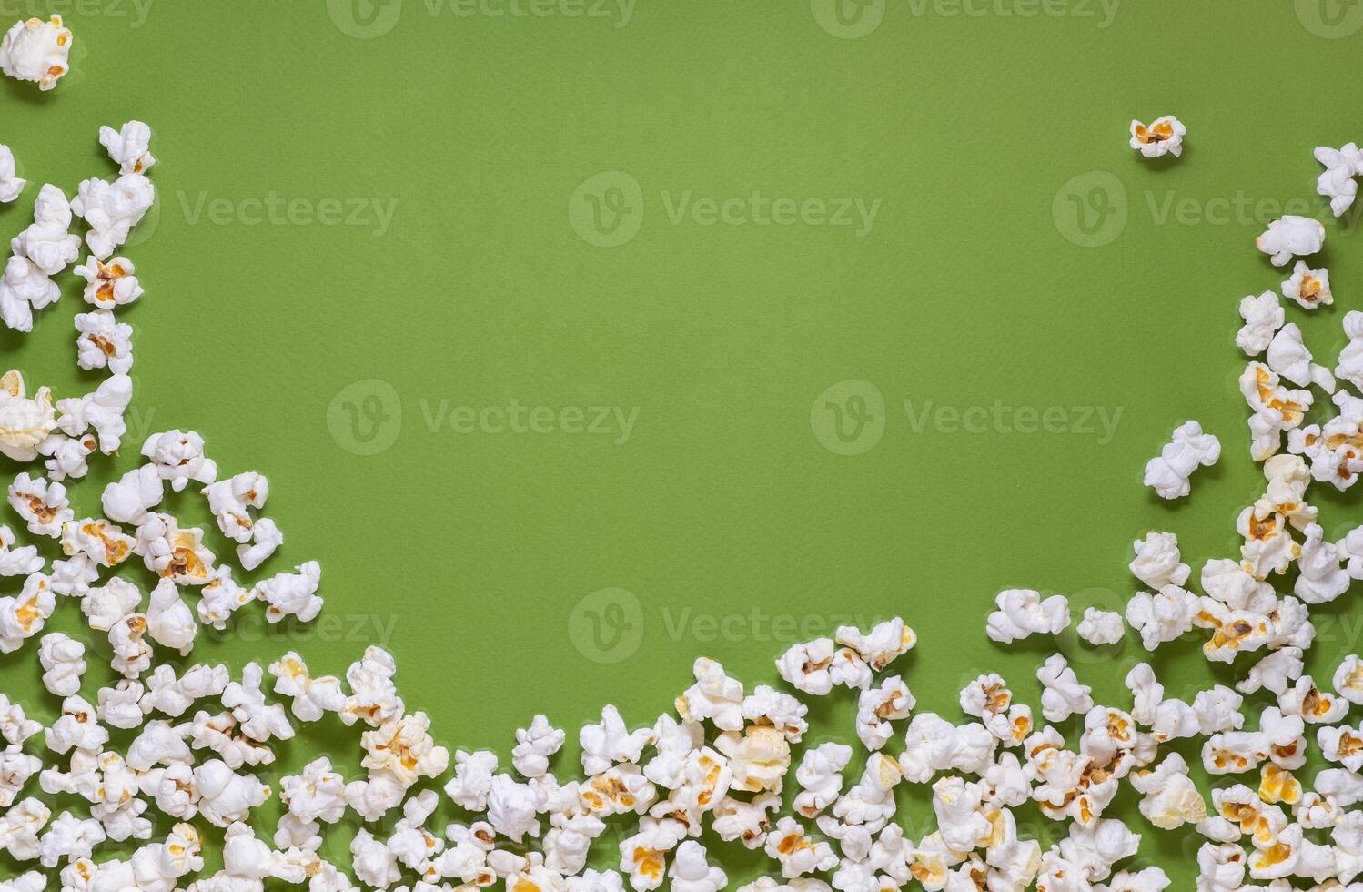 White tasty popcorn on a green background. Popcorn pattern on green background. Top view. Copyspace for your text. photo