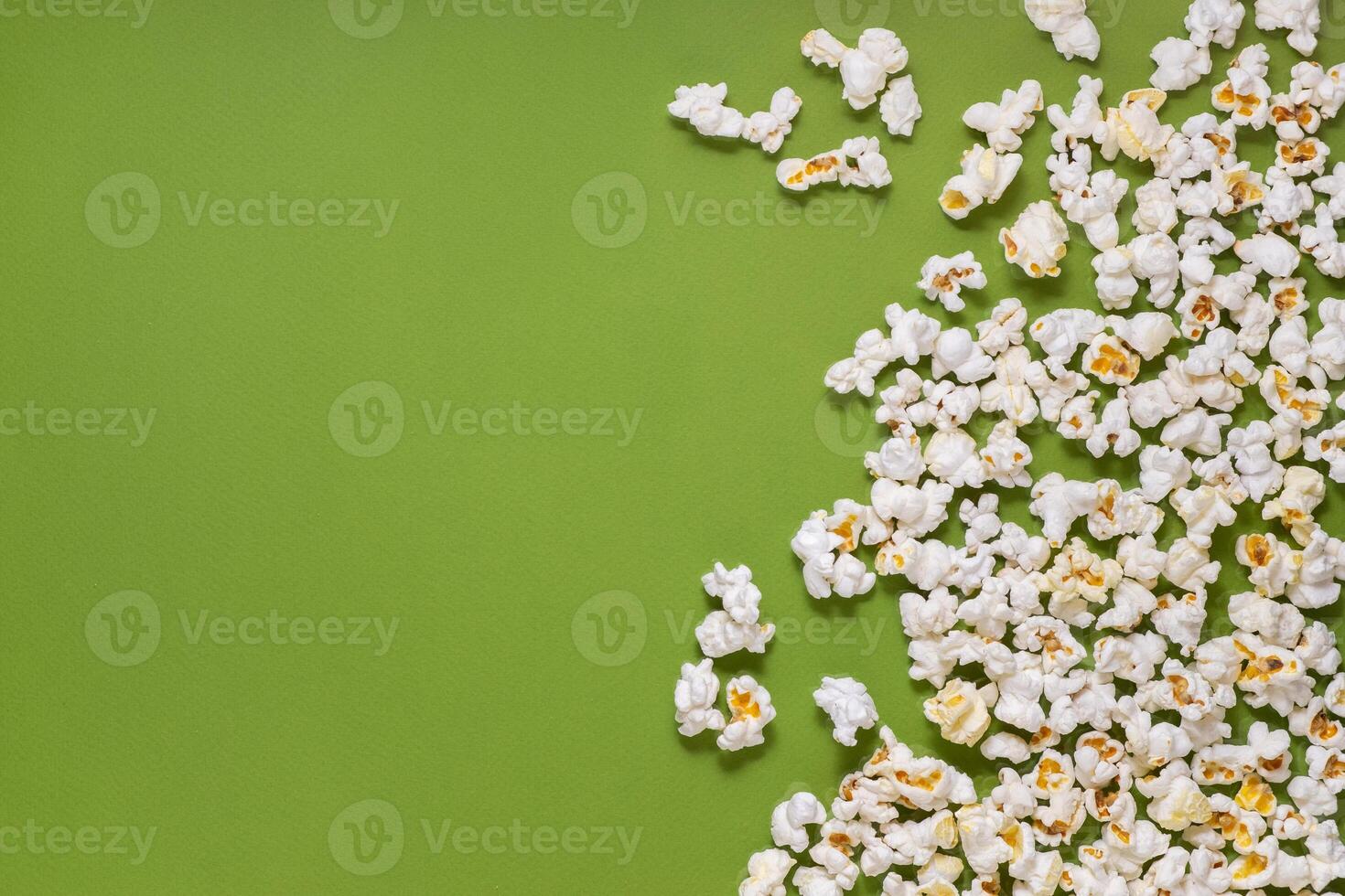 White tasty popcorn on a green background. Popcorn pattern on green background. Top view. Copyspace for your text. photo