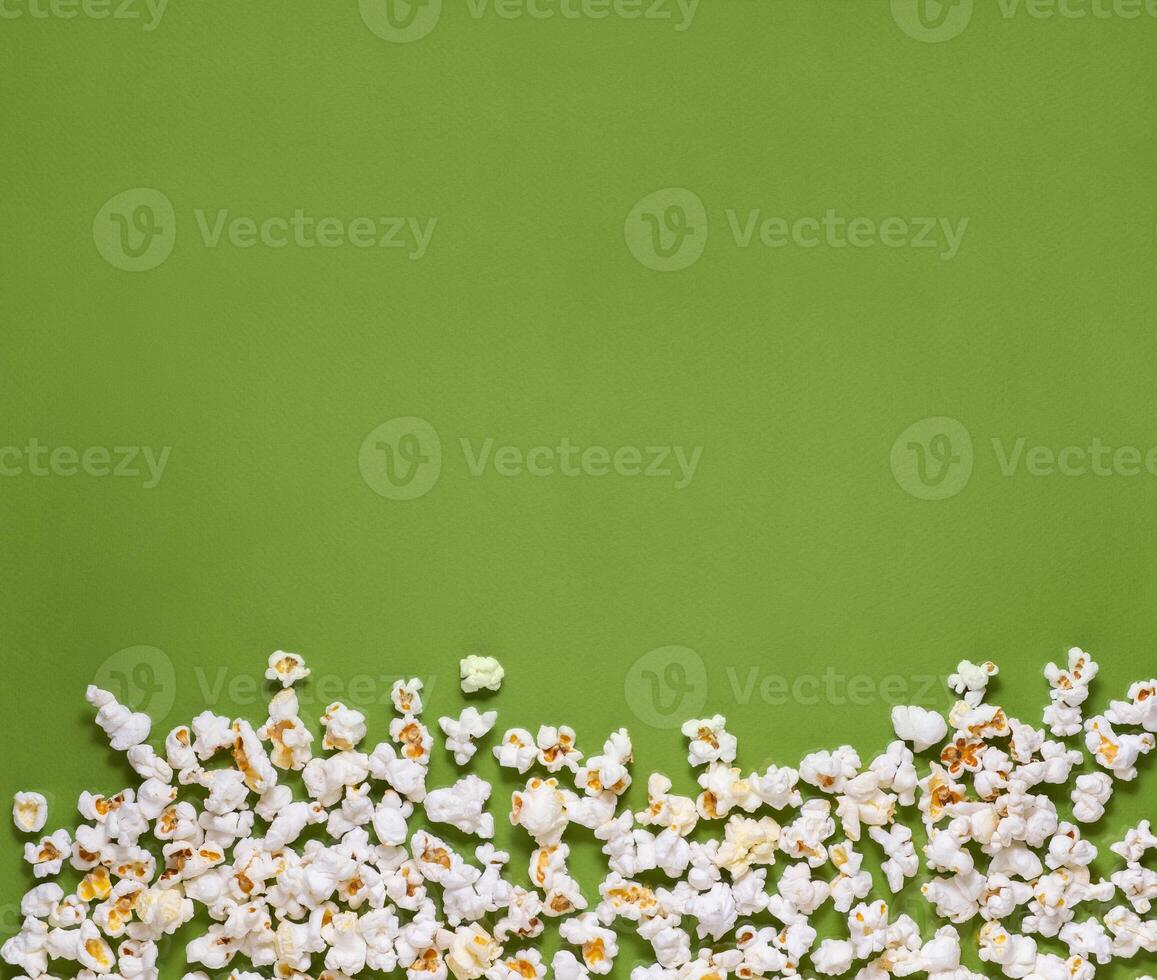 White tasty popcorn on a green background. Popcorn pattern on green background. Top view. Copyspace for your text. photo