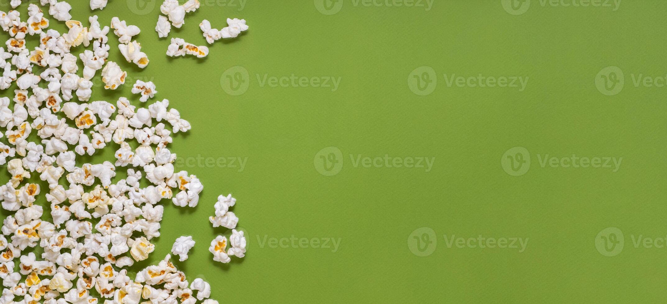 White tasty popcorn on a green background. Popcorn pattern on green background. Top view. Copyspace for your text. photo