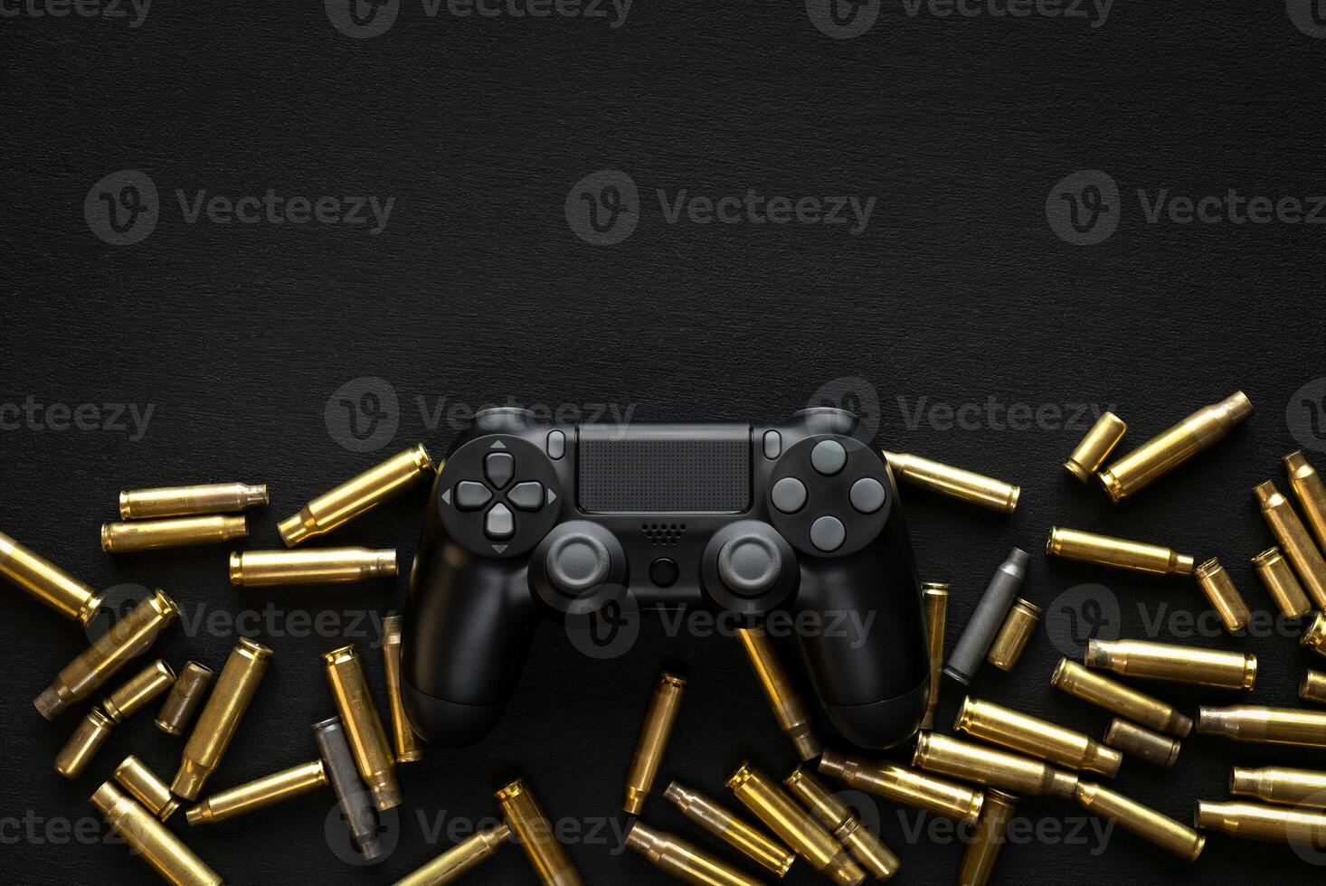 Modern black gamepad on a black background among the spent cartridges. Game concept. Shooter game. photo
