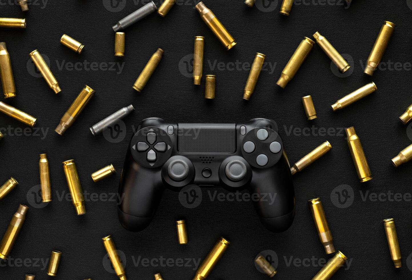 Modern black gamepad on a black background among the spent cartridges. Game concept. Shooter game. photo