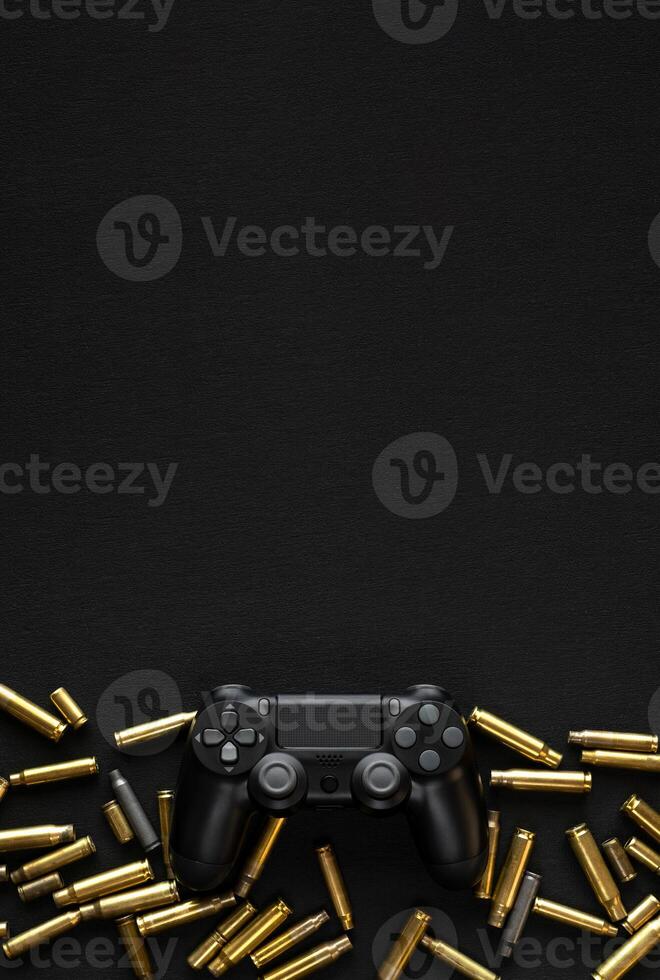 Modern black gamepad on a black background among the spent cartridges. Game concept. Shooter game. photo