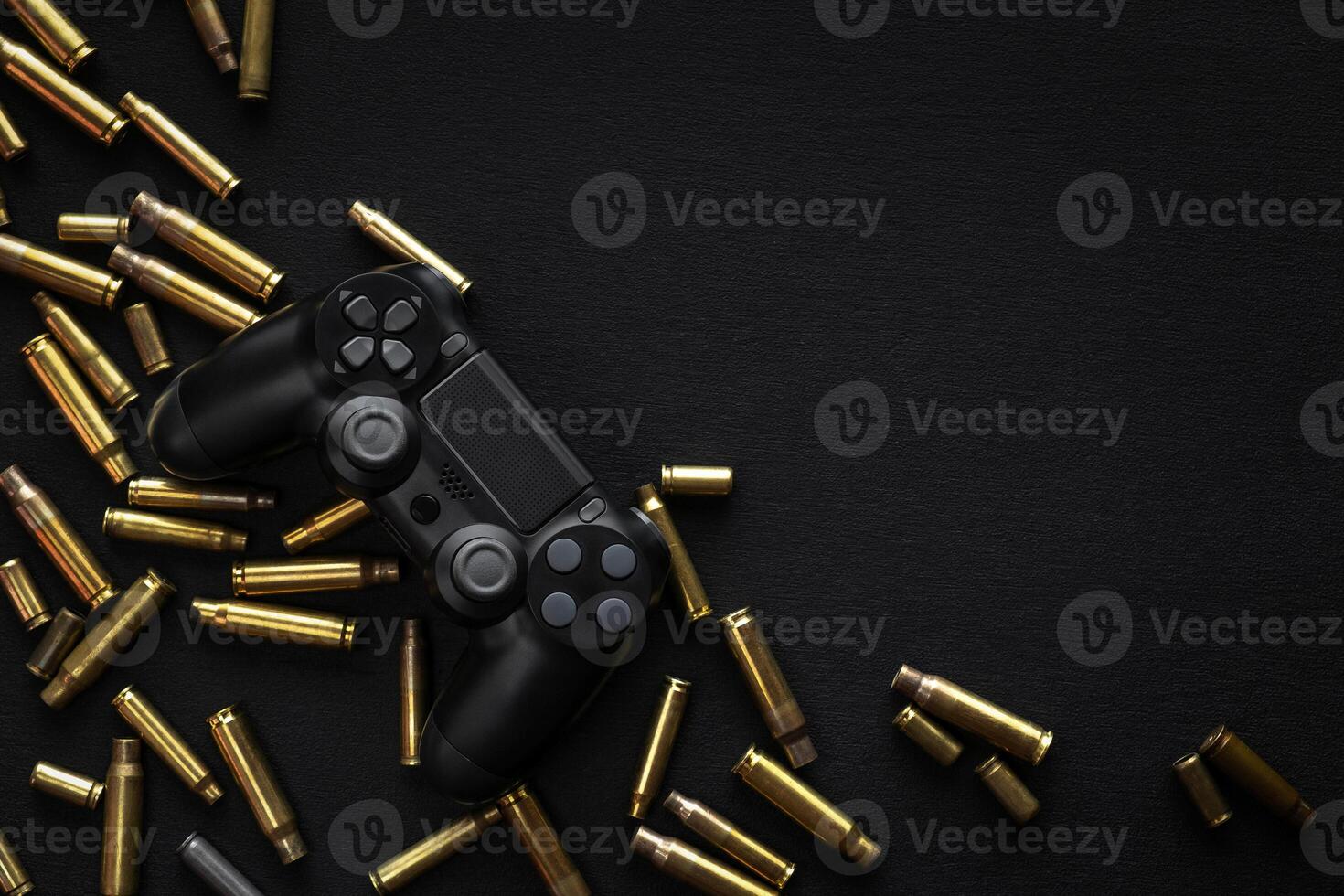 Modern black gamepad on a black background among the spent cartridges. Game concept. Shooter game. photo