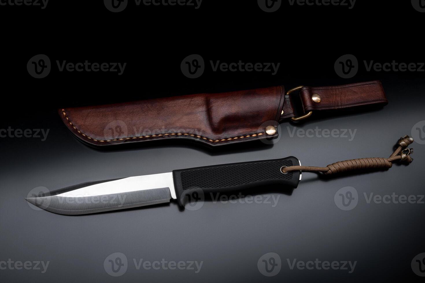 A modern hunting knife and a leather case for him on a dark background. Melee weapons for hunting and self-defense. The instrument of crime. photo