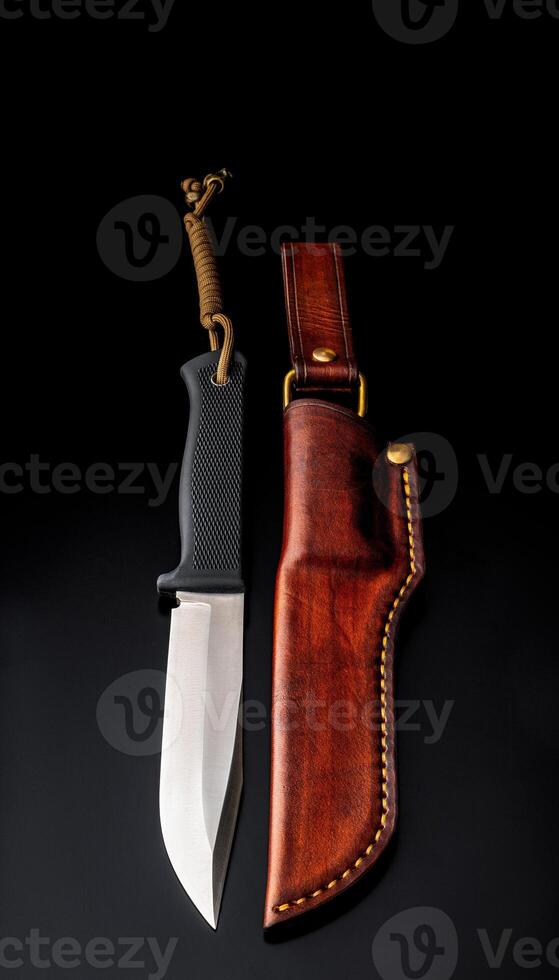 A modern hunting knife and a leather case for him on a dark background. photo