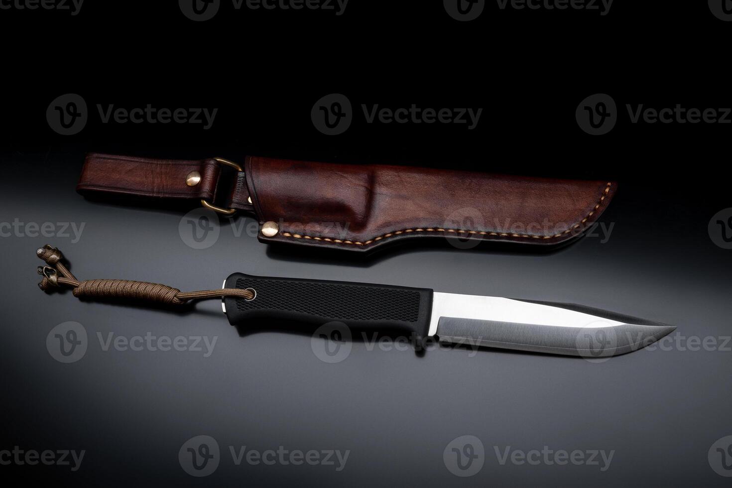 A modern hunting knife and a leather case for him on a dark background. Melee weapons for hunting and self-defense. The instrument of crime. photo