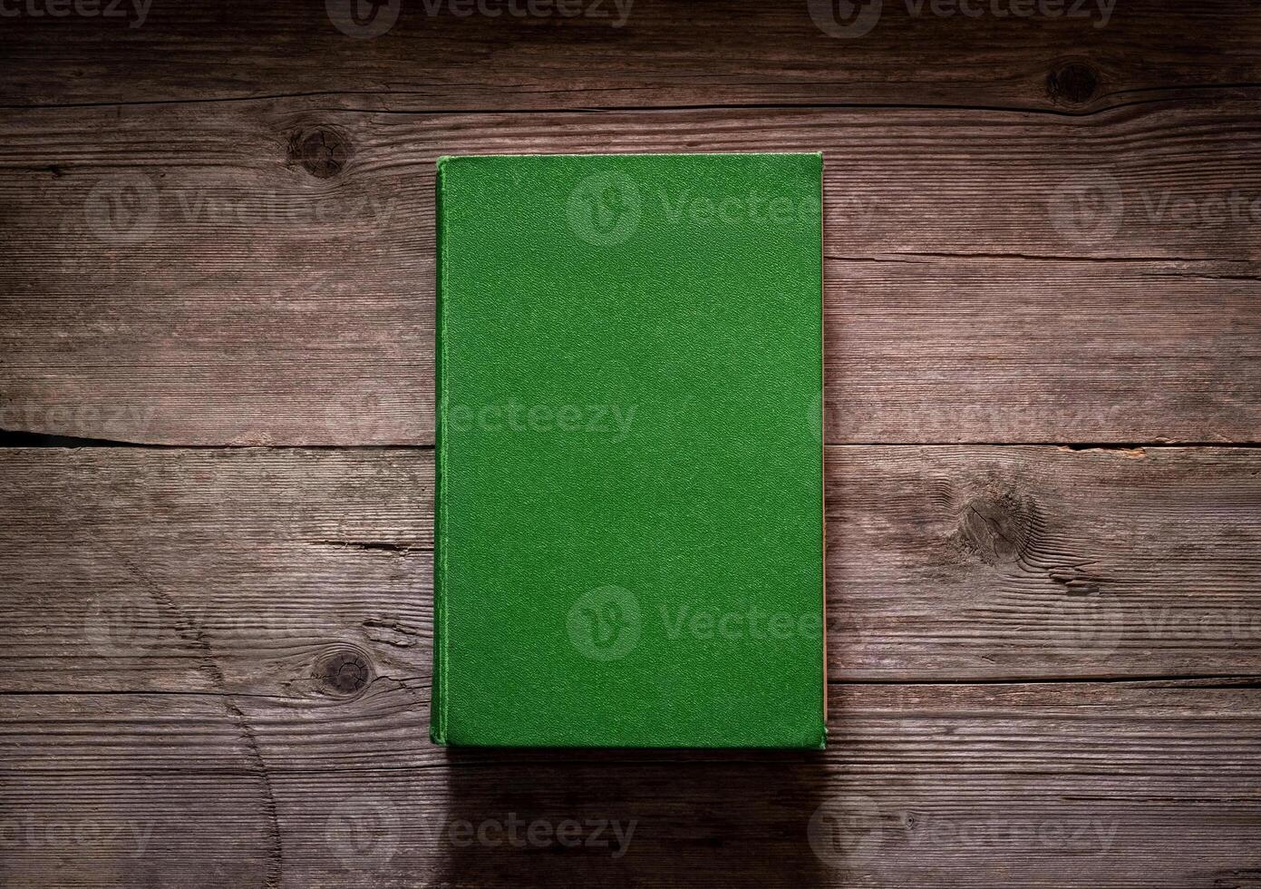 Closed book on vintage wooden background. Old book on the wooden table. Closed book with empty cover laying on wooden table. photo