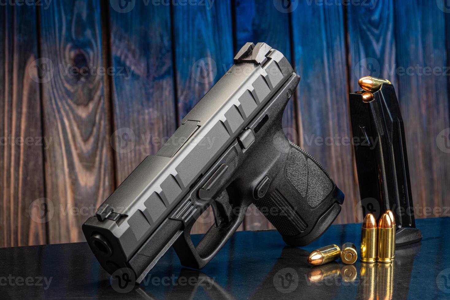 Pistol and cartridges for it on a wooden background. A short-barreled weapon for self-defense photo