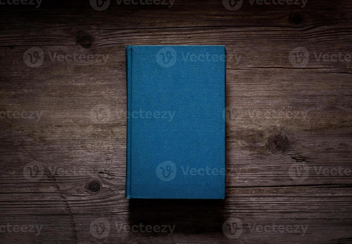 Closed book on vintage wooden background. Old book on the wooden table. Closed book with empty cover laying on wooden table. photo