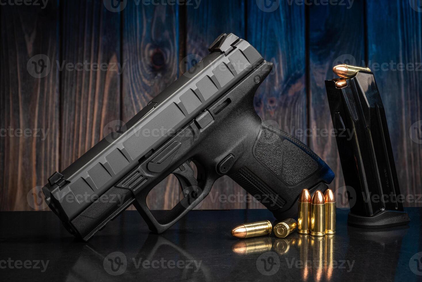 Pistol and cartridges for it on a wooden background. A short-barreled weapon for self-defense photo