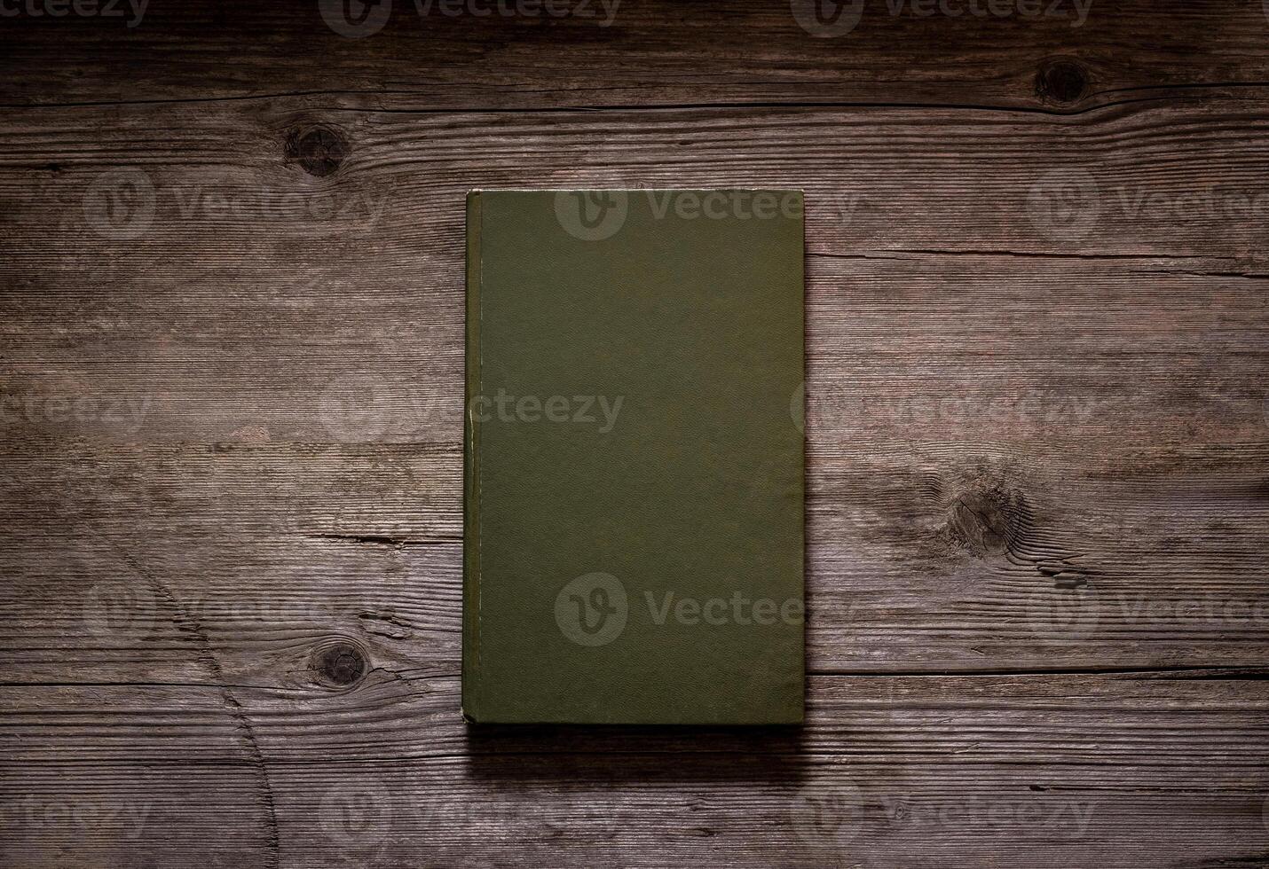 Closed book on vintage wooden background. Old book on the wooden table. Closed book with empty cover laying on wooden table. photo
