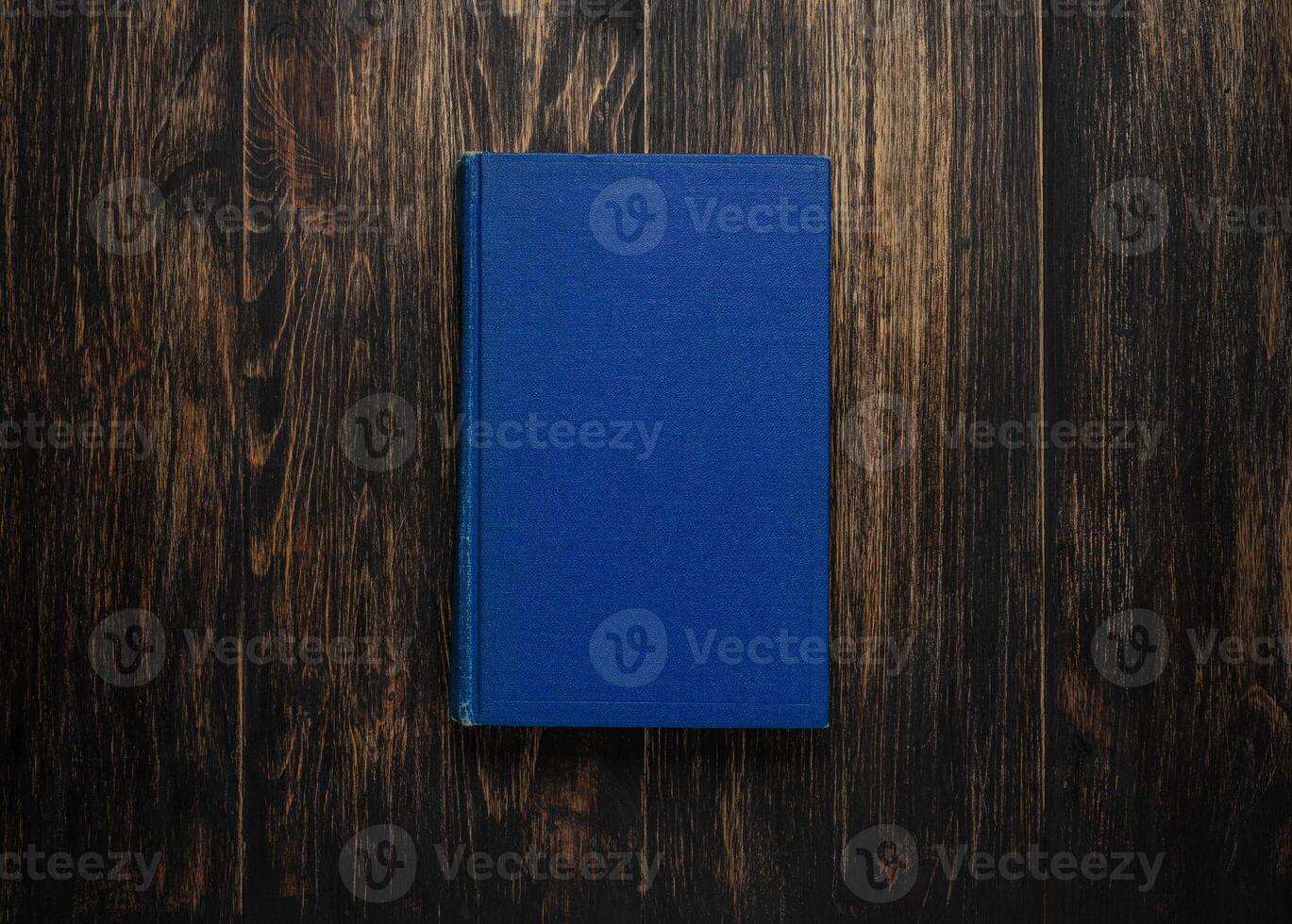 Closed book on vintage wooden background. Old book on the wooden table. Closed book with empty cover laying on wooden table. photo