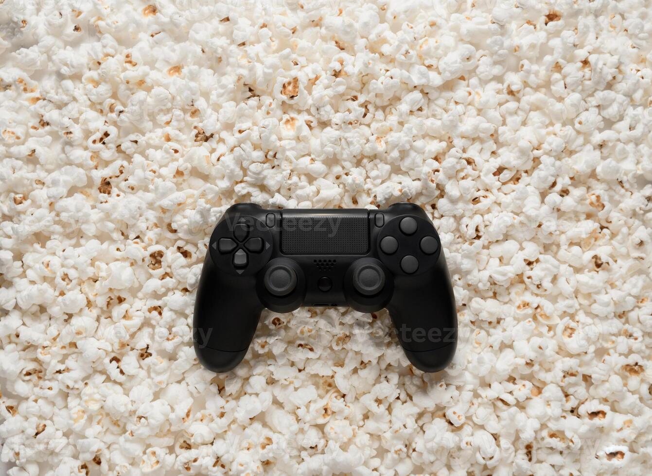 Black gamepad on popcorn back. Game poster or postcard concept. Rest for the game and popcorn. photo