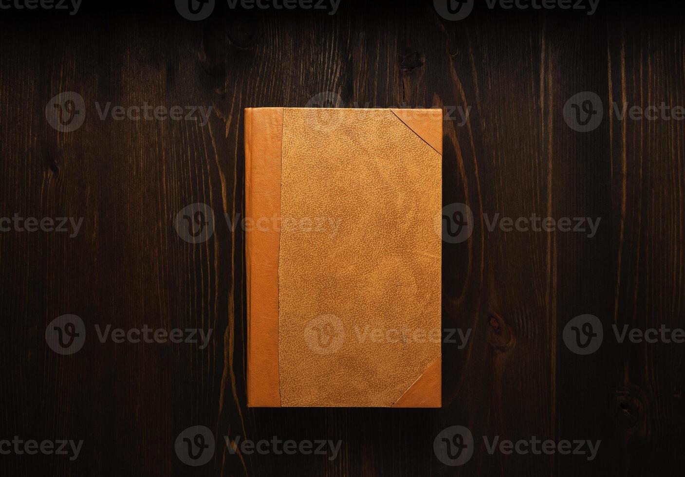 Closed book on vintage wooden background. Old book on the wooden table. Closed book with empty cover laying on wooden table. photo