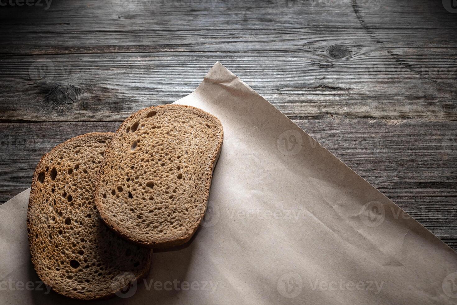 Two slices of black rye bread on an old wooden table. Simple rural still life photo