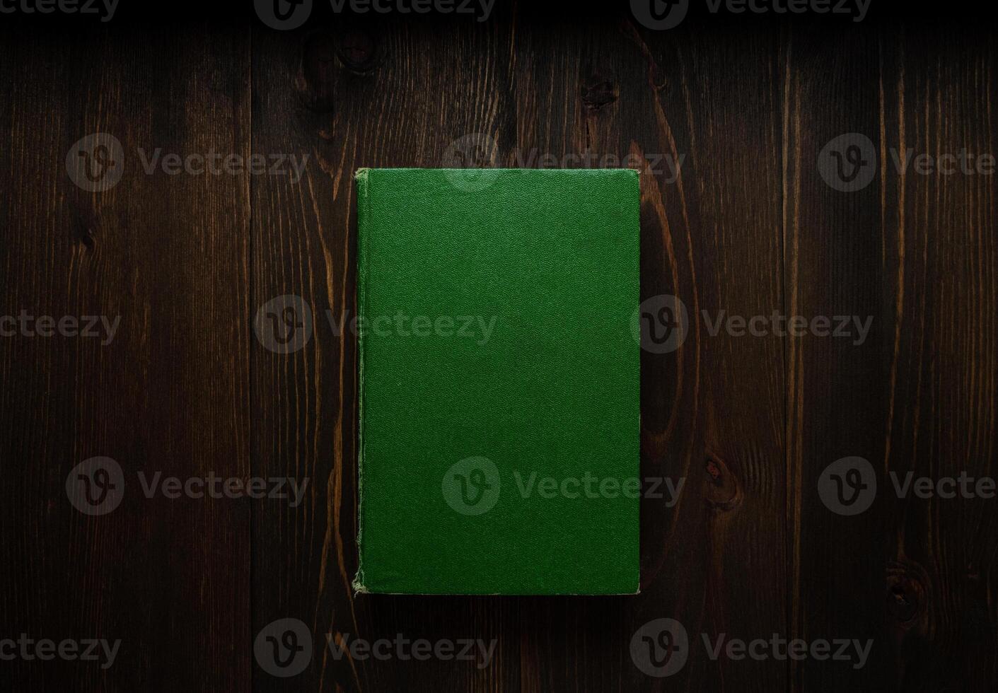 Closed book on vintage wooden background. Old book on the wooden table. Closed book with empty cover laying on wooden table. photo