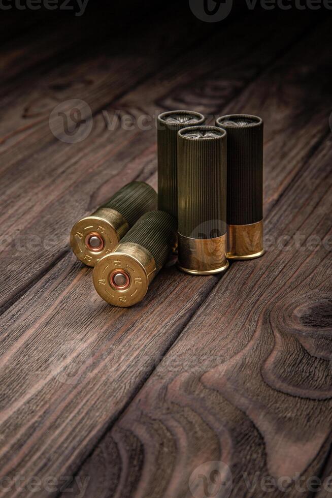Shotgun cartridges on a brown wooden table. Ammunition for 12 gauge smoothbore weapons. photo