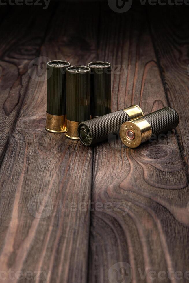 Shotgun cartridges on a brown wooden table. Ammunition for 12 gauge smoothbore weapons. photo