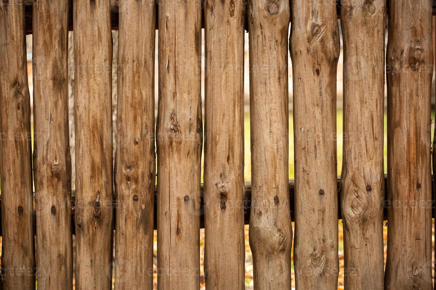 A fence made of roughly processed boards. A palisade of rough logs. Wood back photo