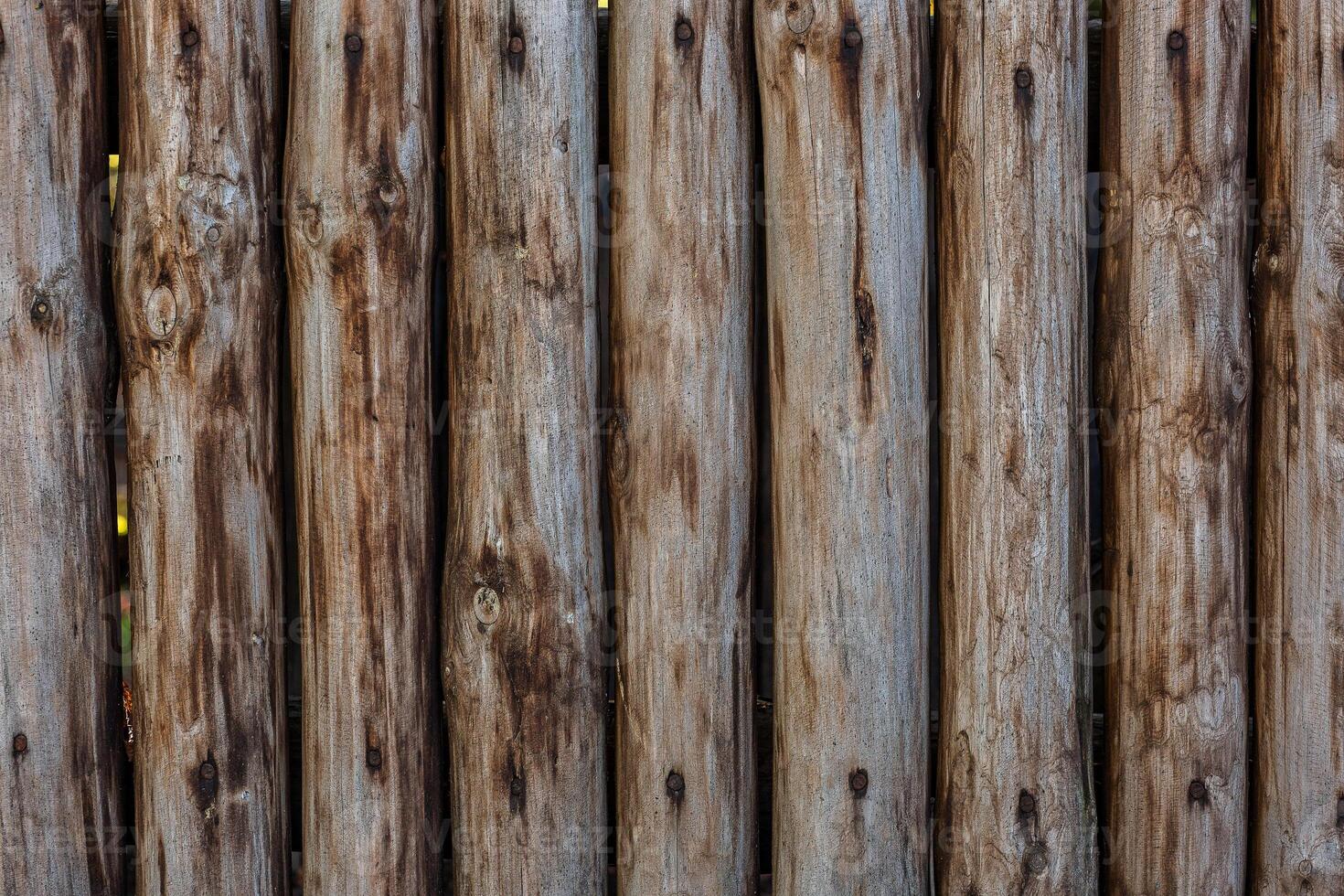 A fence made of roughly processed boards. A palisade of rough logs. Wood back photo