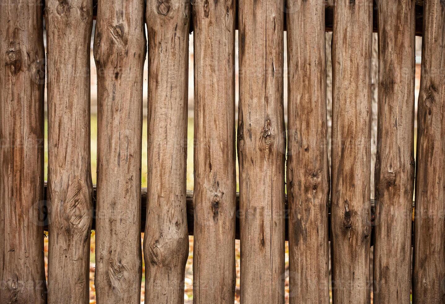 A fence made of roughly processed boards. A palisade of rough logs. Wood back photo