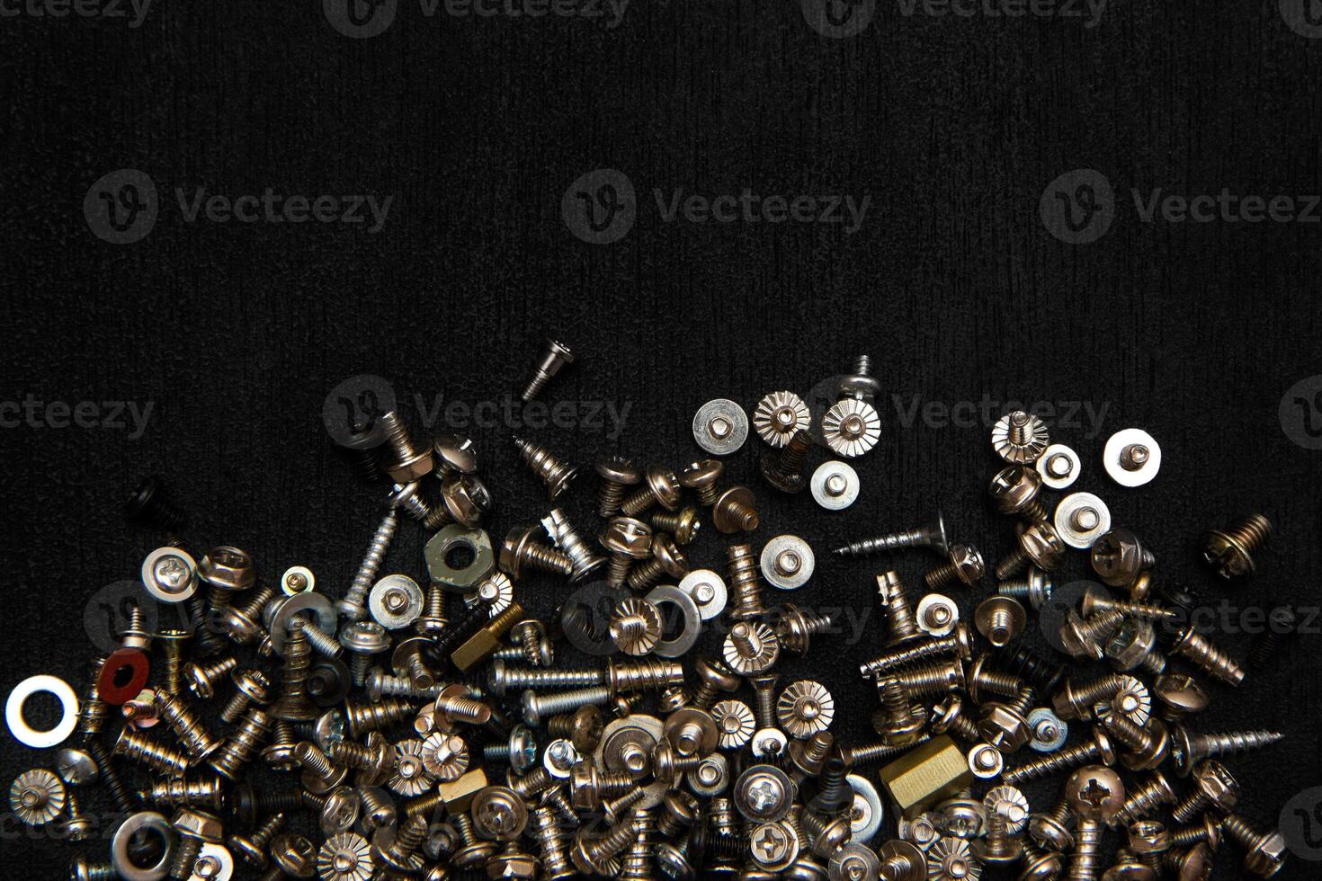 Silvery bolts and screws on a black board photo