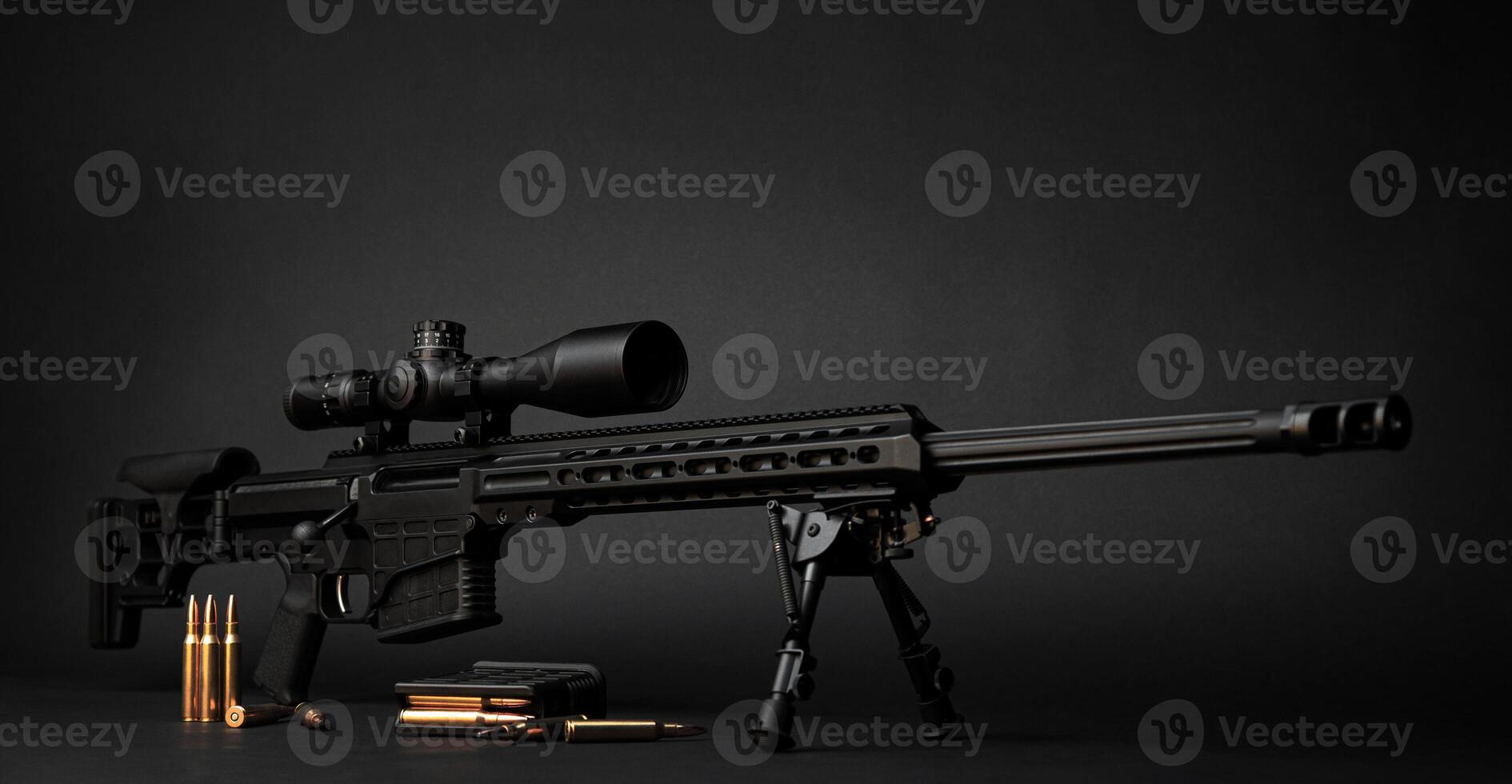 Modern powerful sniper rifle with a telescopic sight mounted on a bipod. Ammo and an additional magazine next to the rifle. photo
