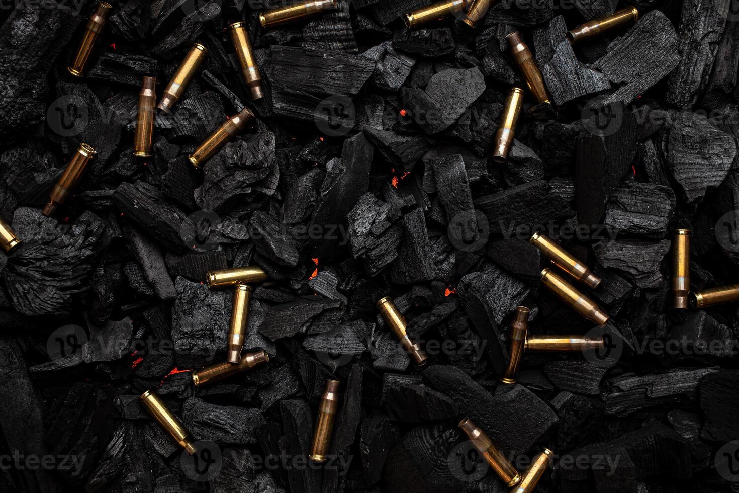 Empty shells from weapons on black smoldering coals. Consequences of the war. Dark back. photo