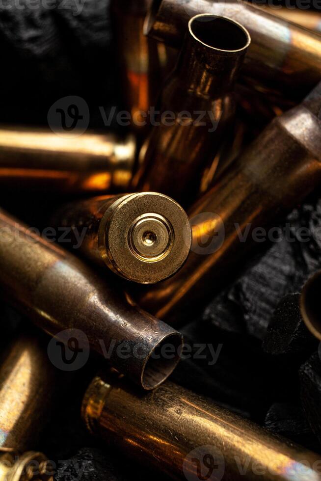 Empty shells from weapons on black smoldering coals. Consequences of the war. Dark back. photo